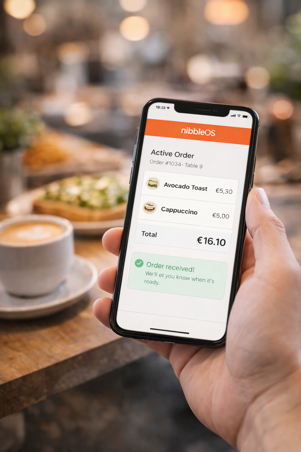 Customer holding a phone showing a NibbleOS order confirmation with items and total in a cafe